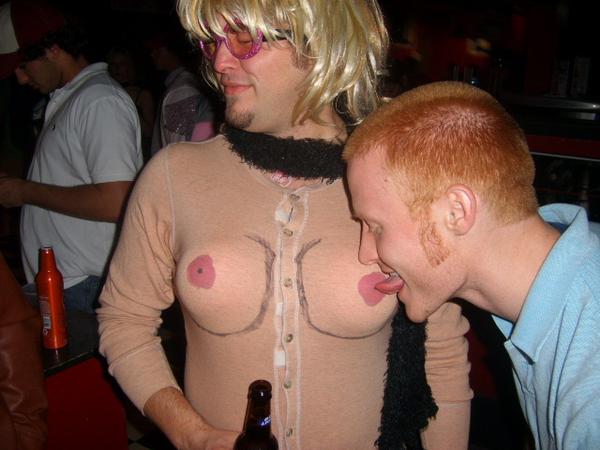 Man dressed as a woman with another licking fake boobie